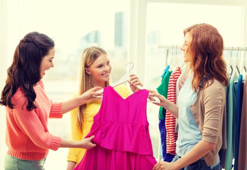 shopping, fashion and friendship concept - three smiling friends trying on some clothes at home or shopping mall