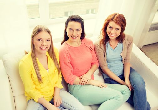 friendship and happiness concept - three girlfriends having a talk at home