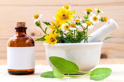 Alternative health care fresh herbal ,oil and wild flower with mortar on wooden background.