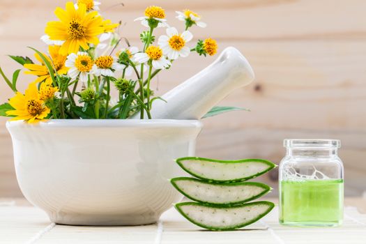 Alternative health care fresh herbal Aloe vera , oil and wild flower with mortar on wooden background.