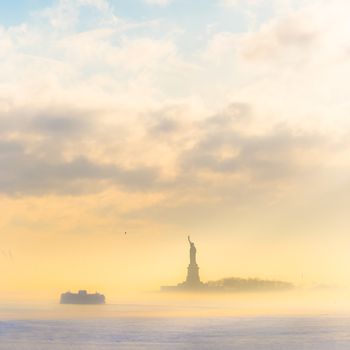 Staten Island Ferry cruises past the Statue of Liberty on a misty sunset. Manhattan, New York City, United States of America. Square composition. Copy space.