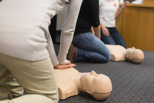 A group of adult education students practitcing CPR chest compressioon on a dummy. 