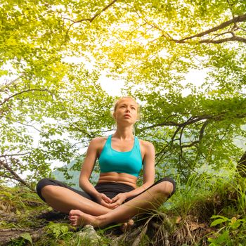 Relaxed woman enjoying freedom and life in beautiful natural environment. Blissful girl feeling relaxed, free and happy. Concept of freedom, happiness, enjoyment and natural balance.