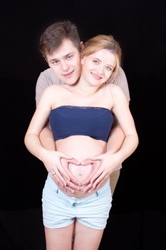 man embraces a woman showing her belly heart
