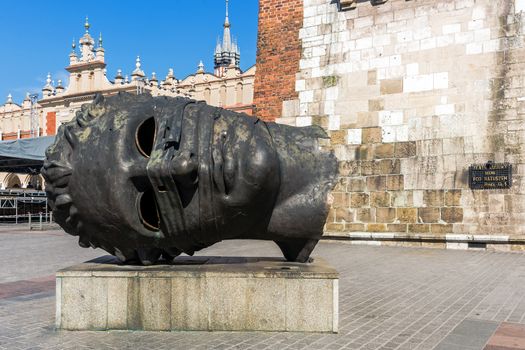 Interesting and ambiguous sculpture "Eros bendato" by Polish artist Igor Mitoraj (1944 – 2014),  in the historical Old Market Square in Krakow, Poland.