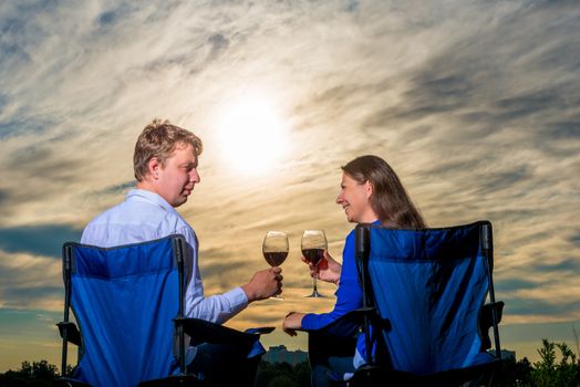 happy young married couple with a glass of wine at sunset