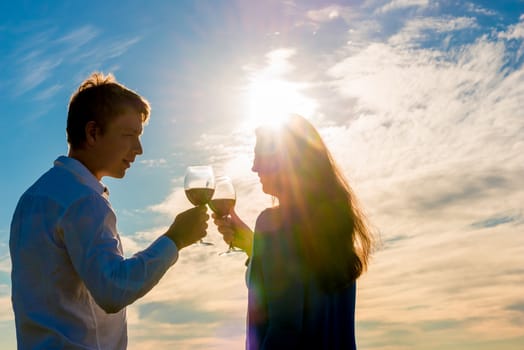 couple with a glass of red wine against the sun