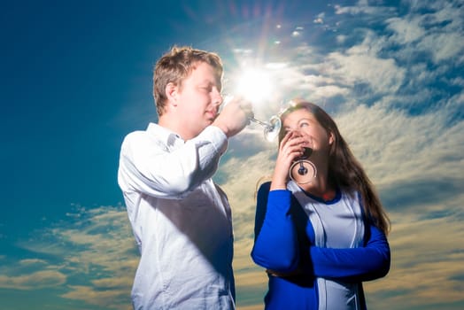 Young couple drinking red wine shot against the sky