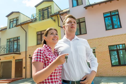 happy couple with the keys in the hands about his new townhouse