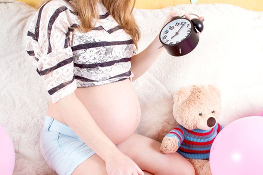 Pregnant woman sitting on the couch with alarm