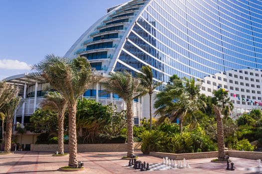Palm trees waving in the wind and giant chess board in front of Jumeirah Beach Hotel in Dubai, wave-shaped luxury resort, well-known Dubai landmark,  on February 3, 2013, UAE.