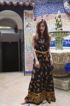 A girl in black bohemian dress in front of colorful mosaic wall