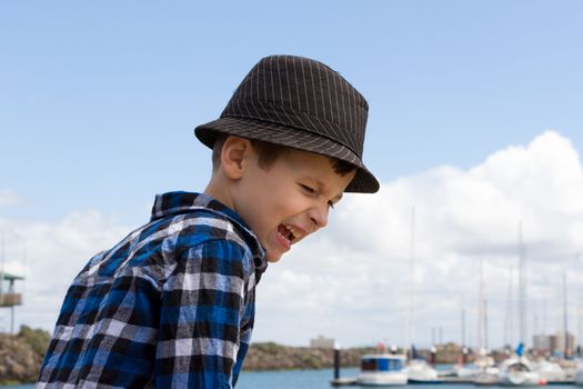 A young boy playing and screaming at a boat harbour.