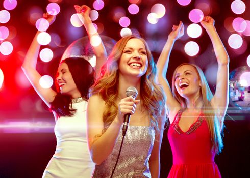 new year, celebration, friends, bachelorette party, birthday concept - three women in evening dresses dancing and singing karaoke