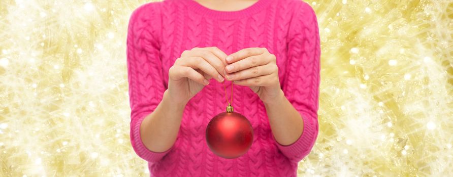 christmas, decoration, holidays and people concept - close up of woman in pink sweater holding christmas ball over yellow background