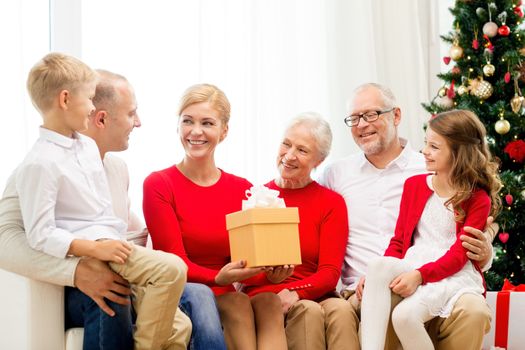 family, holidays, generation, christmas and people concept - smiling family with gift boxes sitting on couch at home