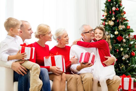 family, holidays, generation, christmas and people concept - smiling family with gift boxes sitting on couch at home