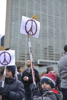 CANADA, Toronto: A boy holds up a peace sign featuring the Eiffel Tower attached to a hockey stick as hundreds gather at Nathan Phillips Square in Toronto on November 14, 2015, a day after a series of terror attacks in Paris. Islamic State has claimed responsibility for the attacks, which killed at least 129 people and left hundreds more injured in scenes of carnage at a concert hall, restaurants and the national stadium on Friday, November 13.