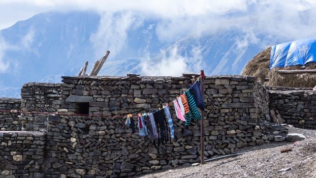 The colorful clothes drying in the wind, the haystack and the Caucasus Mountains in the background. The village of Xinaliq, Azerbaijan.