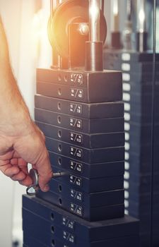 Hand of man adjusting the weight in exercise machine