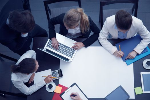 Business workplace with people, cup of coffee, digital tablet, smartphone, papers and various office objects on table