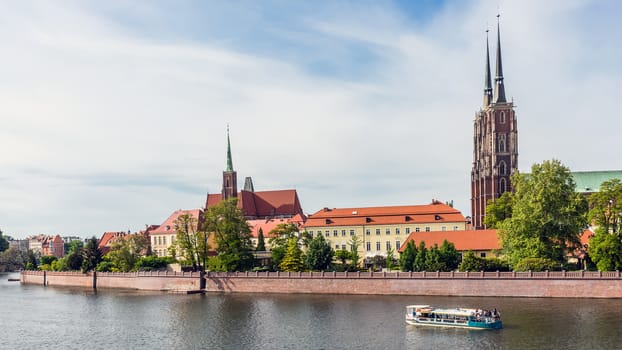 Pleasure boat on the Oder river passes Ostrow Tumski, the oldest part of Wroclaw with The Cathedral of St. John the Baptist and The Church of the Holy Cross.