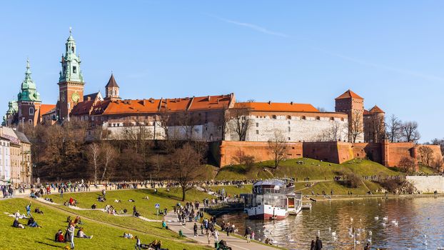 People walk along the boulevard at the foot of the Wawel castle hill. Krakow, historical seat of Polish kings, is the most popular destination in Poland.