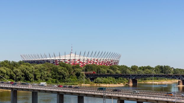 The Polish National Stadium in Warsaw preceded by the Swietokrzyski Bridge over  Vistula river. Designed and constructed for UEFA EURO 2012 tournament co-hosted by Poland and Ukraine.