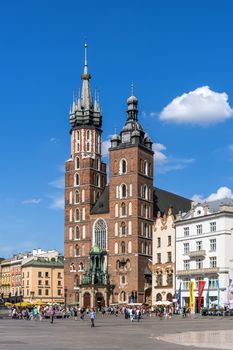 Old Market Square crowded with tourists at the St. Mary's Basilica in Krakow. Brick Gothic church built in the early 13th century is the main landmark of the city.