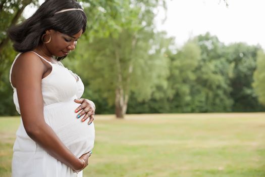 Pregnant african woman in nature with white dress