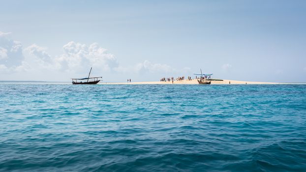 Pictured a small atoll that appears at low tide and disappears with the high tide, formed by white sand near the island of Zanzibar and visited daily by tourists.