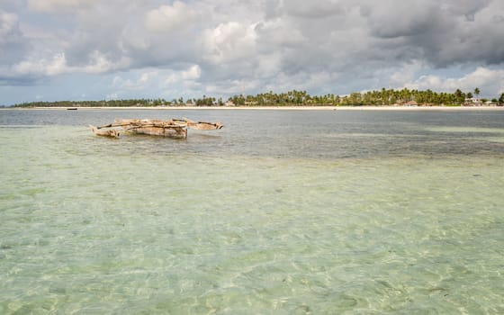 Pictured typical fishing boat anchored in the bay in the island of Zanzibar, Tanzania and background in a fishing village.