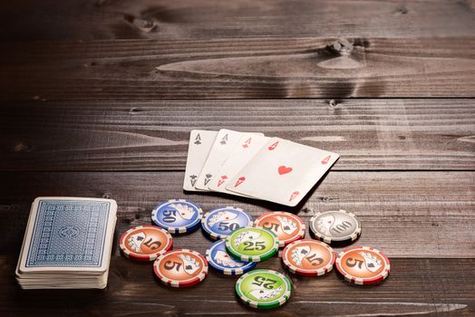 Four aces and chips, vintage poker game playing cards on a wood table