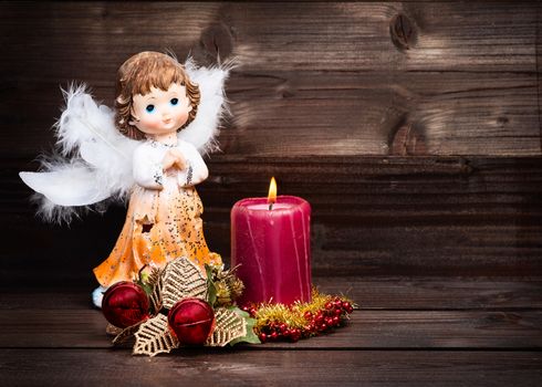 Christmas greeting card with candle and angels on wooden background.