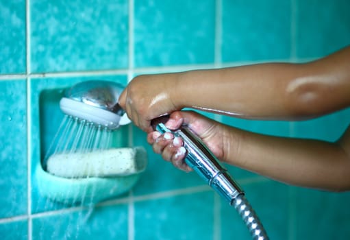 In the bathroom, a child holding a shower head