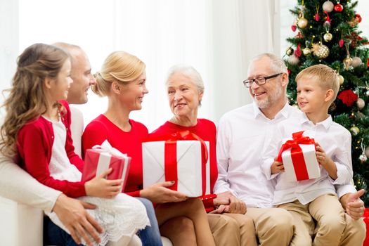 family, holidays, generation, christmas and people concept - smiling family with gift boxes sitting on couch at home