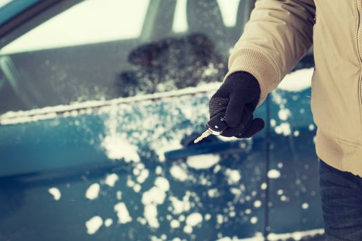 transportation and ownership concept - closeup of man hand with car key outdoors