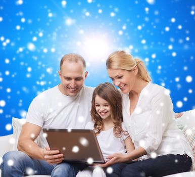 family, christmas, holidays, technology and people concept - smiling family with laptop computer over blue snowy background