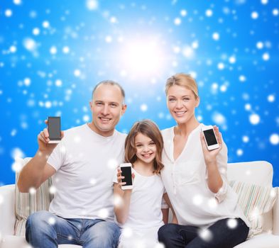 christmas, holidays, technology, advertisement and people concept - smiling family with smartphones over blue snowy background