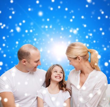 family, childhood, holidays and people - smiling mother, father and little girl over blue snowy background