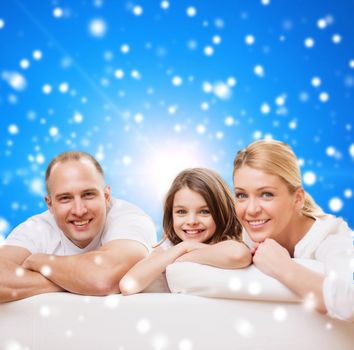 family, childhood, holidays and people - smiling mother, father and little girl over blue snowy background