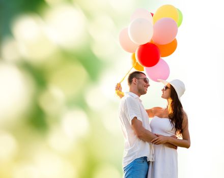 love, wedding, summer, dating and people concept - smiling couple wearing sunglasses with balloons hugging over green background