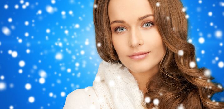 happiness, winter holidays, christmas and people concept - close up of smiling young woman in white warm clothes over blue snowy background