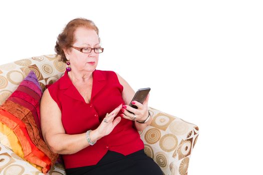 Senior Woman Sitting on a Couch While Reading Messages on her Mobile Phone, Isolated on White.