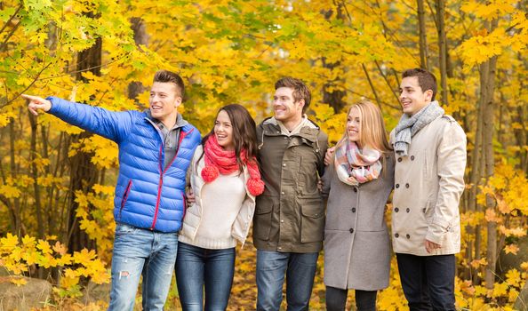 love, relationship, season, friendship and people concept - group of smiling men and women hugging in autumn park