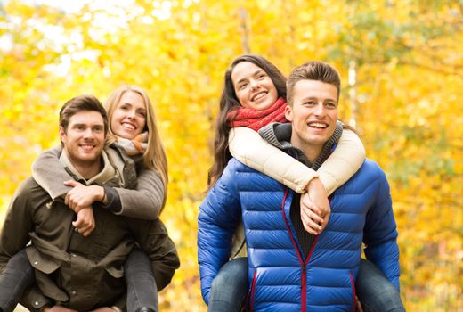 love, friendship, family and people concept - smiling friends having fun in autumn park