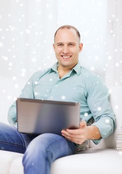 technology, business and lifestyle concept - smiling man working with laptop at home