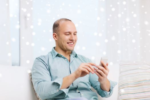 communication, technology and people concept - smiling man with smartphone at home