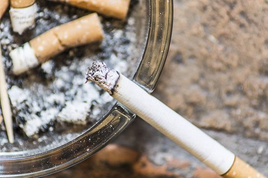 cigarettes on an ashtray with one still smoking