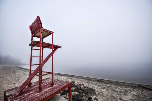 A lonely lifeguard seat stands empty in the fog on a November beach in Ontario Canada.